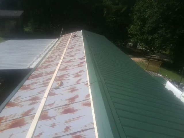 Old rusted panels beside newly installed green metal roofing — Wind Damage Roof Repair by Roofing Brothers in Prescott